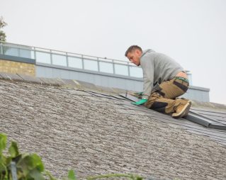 Construction worker installing roof shingles — Florida 25 percent roof replacement rule